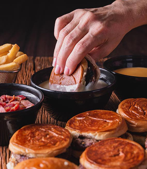 Fotografia apetitosa do Fondue Burger com os mini burgers suculentos, o molho de queijo cheddar derretido e as irresistíveis lascas de bacon.